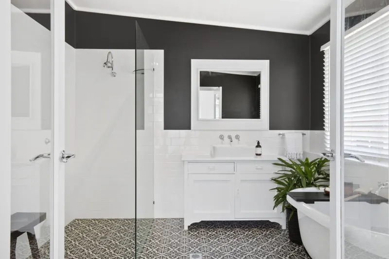 Black and white bathroom with a walk-in shower, freestanding bath and patterned floor tiles