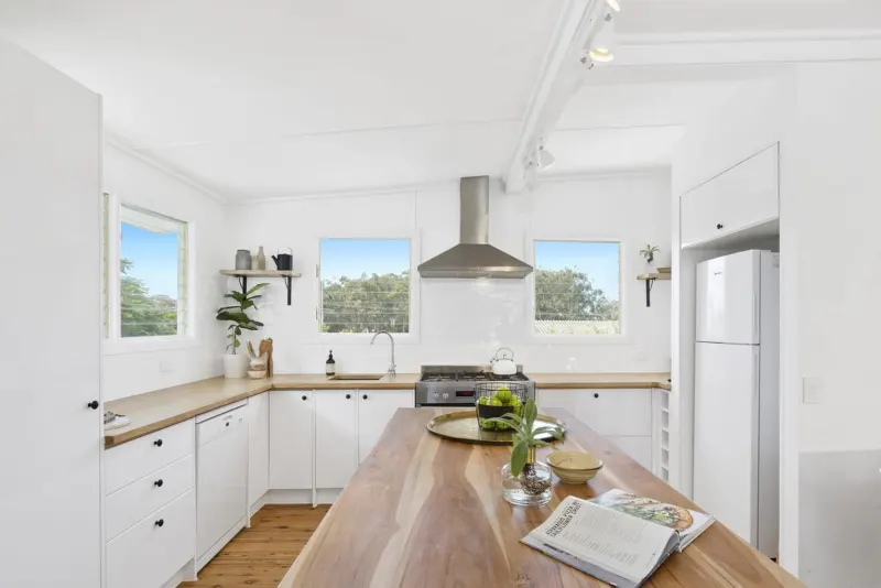 White kitchen with a timber benchtop and timber floor